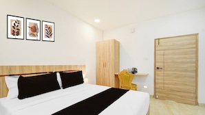 Una habitación de hotel con una cama, un armario de madera, una silla y una puerta.