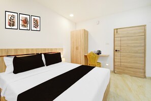 Een hotelkamer met een bed, een houten kast, een stoel en een deur.