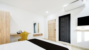 Una habitación de hotel con una cama, una silla, un armario, una puerta y un televisor montado.