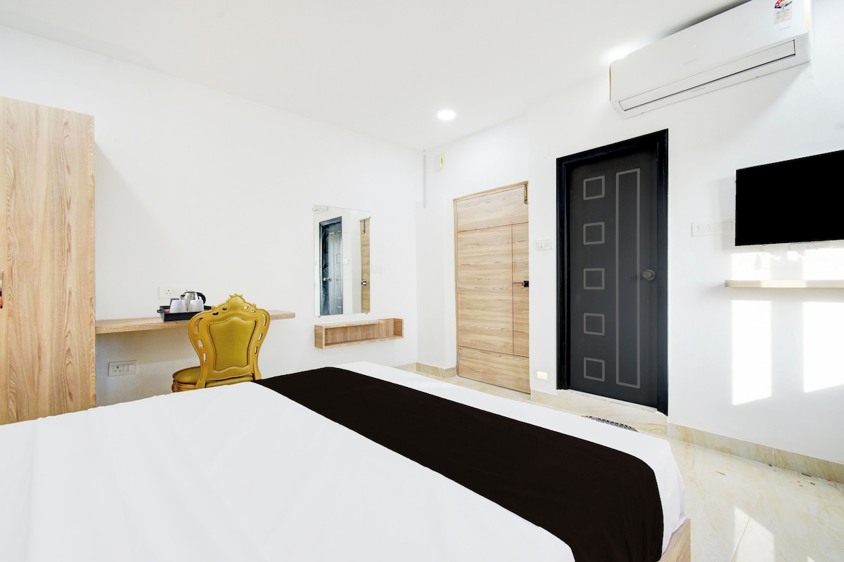 Een hotelkamer met een bed, een stoel, een kledingkast, een deur en een wandtelevisie.