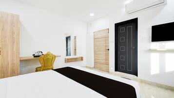 A hotel room with a bed, a chair, a wardrobe, a door, and a mounted TV.