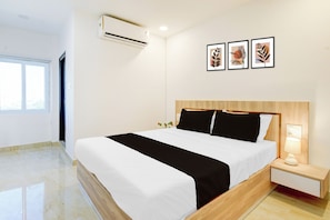 Una habitación de hotel moderna con una cama grande, una mesita de noche con lámpara y aire acondicionado de pared.