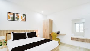 Un dormitorio moderno con una cama grande, un armario de madera, una mesita de noche con una lámpara y una pequeña silla.