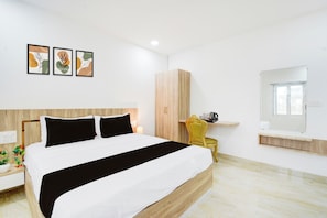 Een moderne slaapkamer met een groot bed, een houten garderobe, een nachtkastje met een lamp en een kleine stoel.