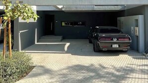 A modern building with a flat roof, large windows, and a car parked in the driveway.