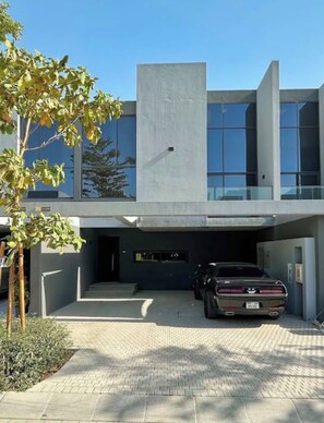 Un edificio moderno con tetto piano, ampie finestre e un'auto parcheggiata nel vialetto.