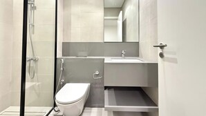 A modern bathroom with a glass-enclosed shower, a white toilet, and a sink with a mirror above.