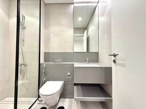 Un bagno moderno con doccia vetrata, un water bianco e un lavabo con specchio sopra.