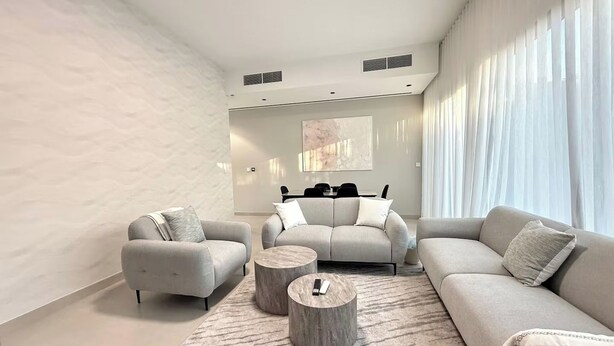 A modern living room with a sofa set, two armchairs, a coffee table, and a rug.