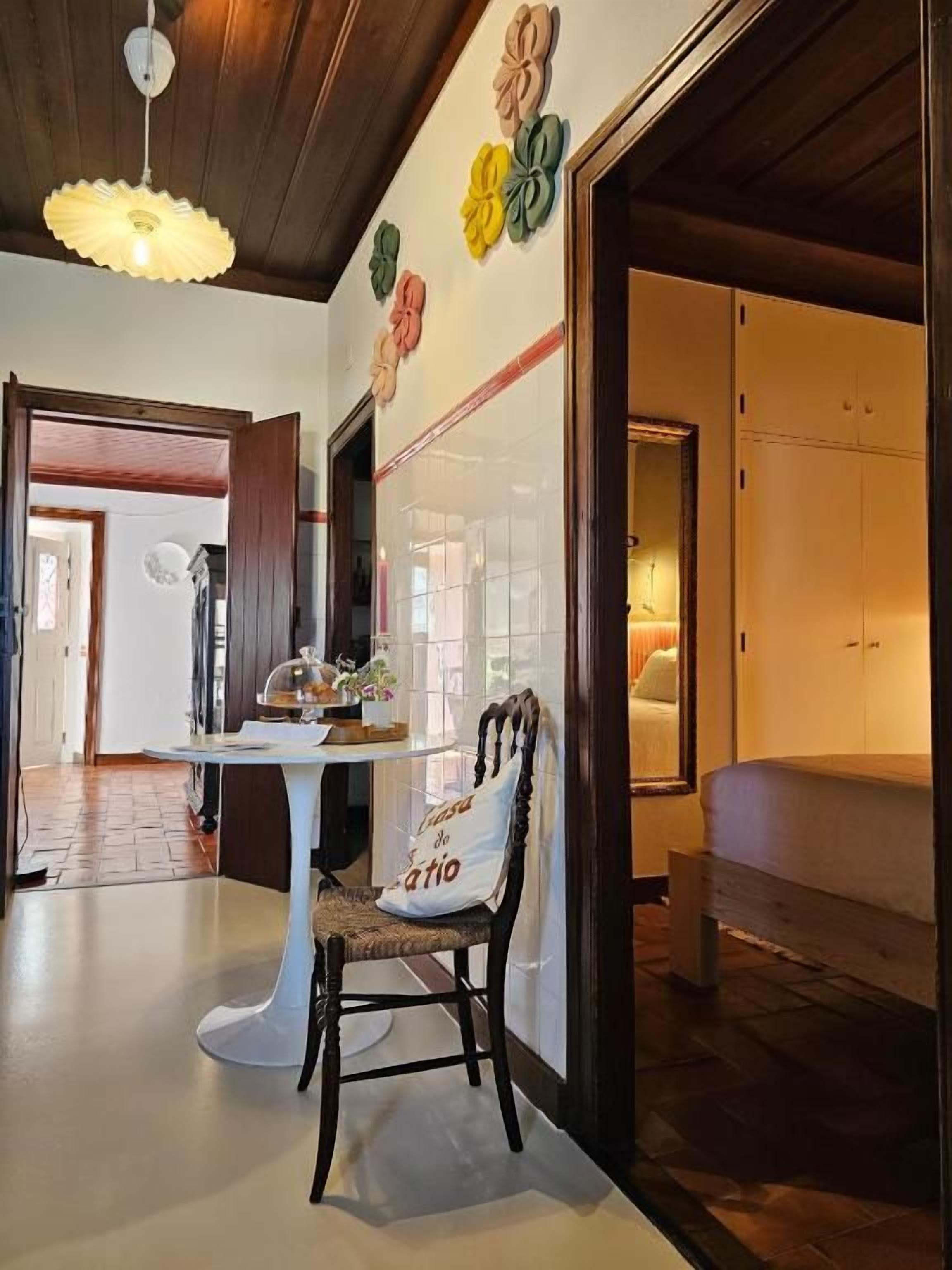 Una habitación con una mesa de comedor, una silla, un sofá, un muro decorativo y una lámpara en el techo.