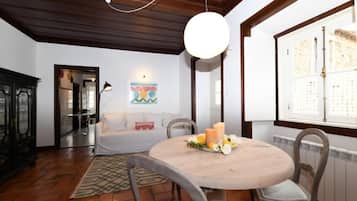 A dining area with a round table, chairs, a hanging light, and a window with a view.
