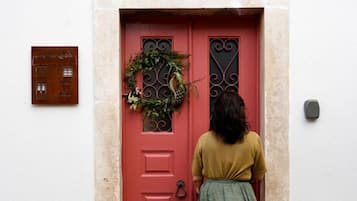 A red door with a wreath, a plaque, and a stone wall.