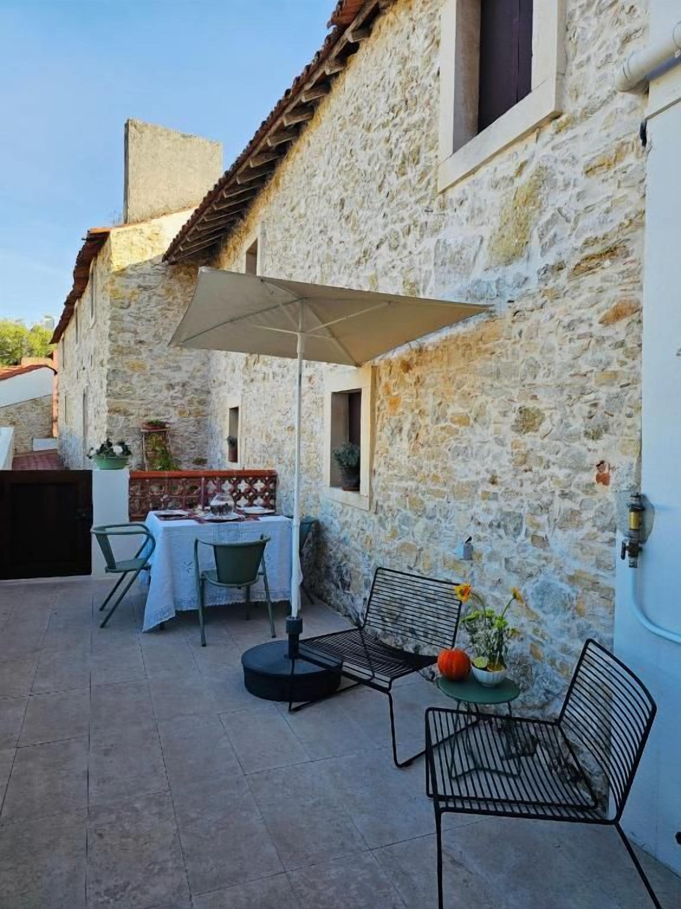 A stone building with a patio area featuring a table, chairs, and an umbrella.