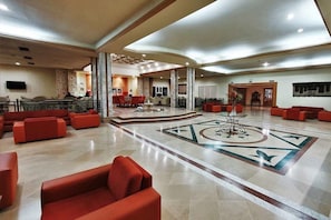 Eine geräumige Lobby mit roter Sitzgelegenheit, einer zentralen Zierbrunnen und einem gemusterten Boden.