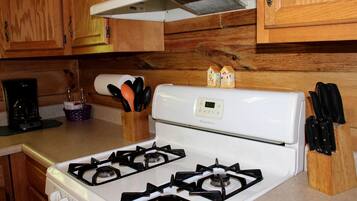 Une cuisine avec un fourneau blanc, des armoires en bois, une machine à café et un bloc à couteaux.