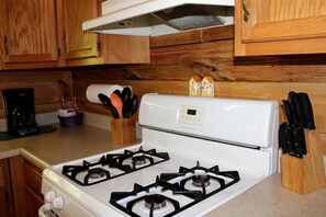 Una cucina con piano cottura bianco, mobili in legno, una macchina da caffè e un portachiodi.