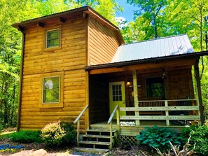 A wooden cabin with a porch and a door labeled 'West'. - Charming Cabin Rental in the Forest near Beckley, West Virginia (Hico)
