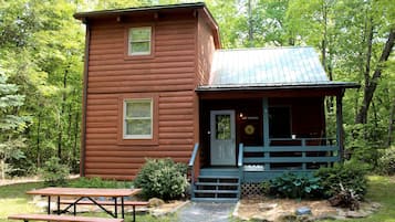 Eine Holzhütte mit Veranda, Picknicktisch und einem Schild mit der Aufschrift 'West Virginia'.