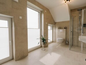A modern bathroom with a shower, toilet, and a large window. - Holiday Apartment in Greetsiel With Balcony (Krummhoern)