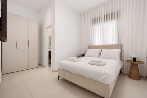Ein Hotelzimmer mit Bett, Nachttisch, Kleiderschrank und einem durchgegangenen Tür sichtbaren Badezimmer.