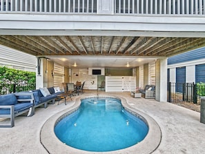 A covered outdoor swimming pool with lounge seating and a television screen. - Luxury Beach House | Private Heated Pool, Lagoon Views & Games | Walk to Beach (Hilton Head Island)
