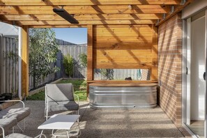 A covered patio area with a hot tub, seating, and a view of a backyard. - Beach & Bath - Torquay Family Getaway (Surf Coast)