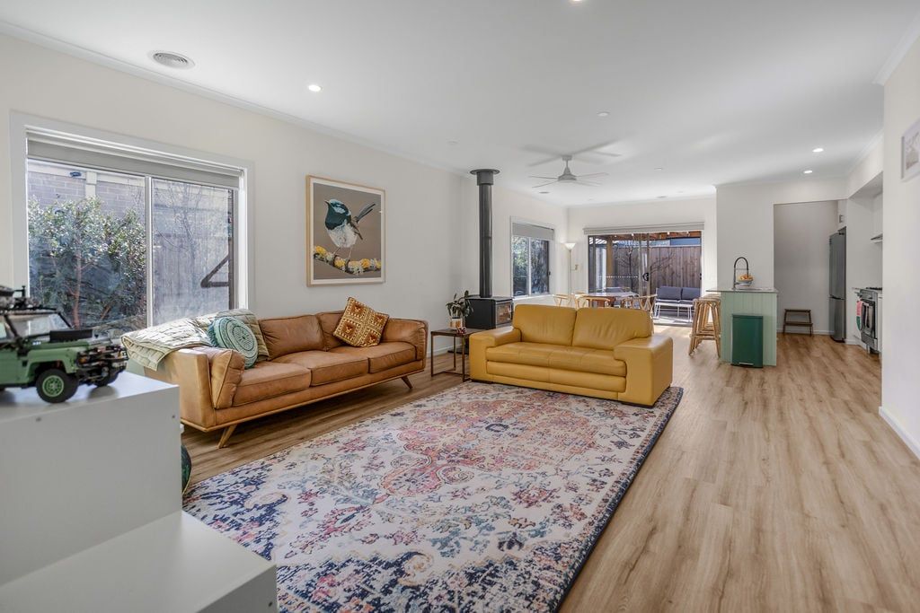 A spacious living area with a large window, a fireplace, and a yellow sofa.