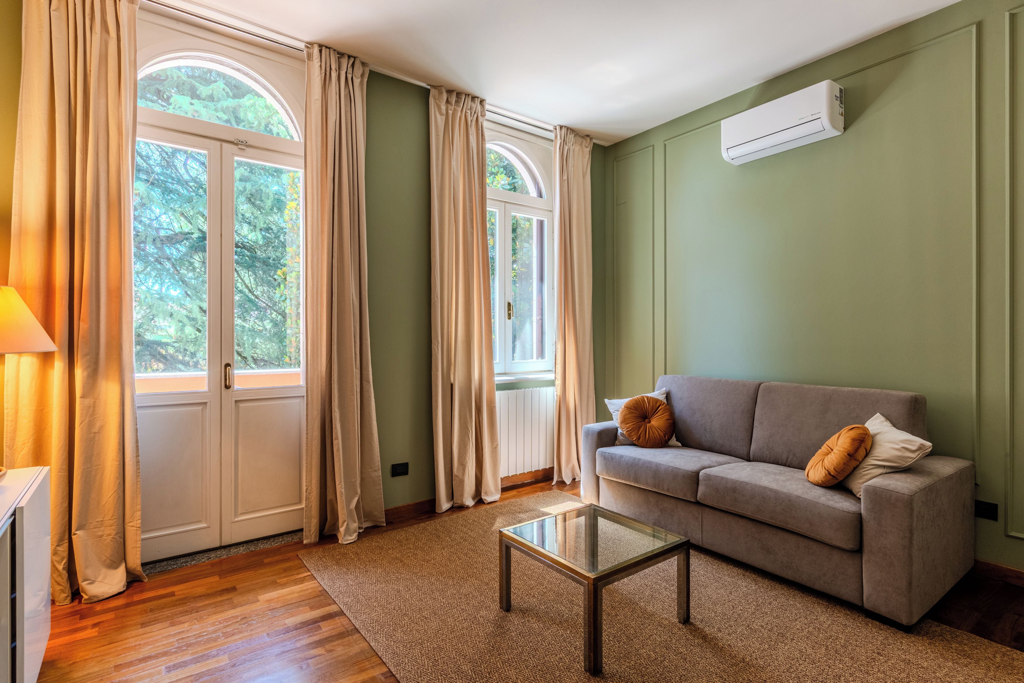 A living room with a sofa, a glass coffee table, and a radiator.
