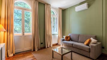 A living room with a sofa, a glass coffee table, and a radiator.
