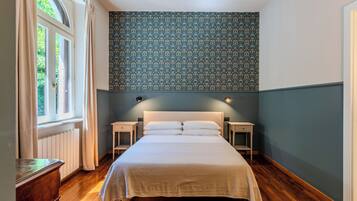 Quarto com uma cama grande, duas mesas de cabeceira, cômoda e uma janela com cortinas.