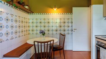 A kitchen with a round table, two chairs, a white door, and a stove.