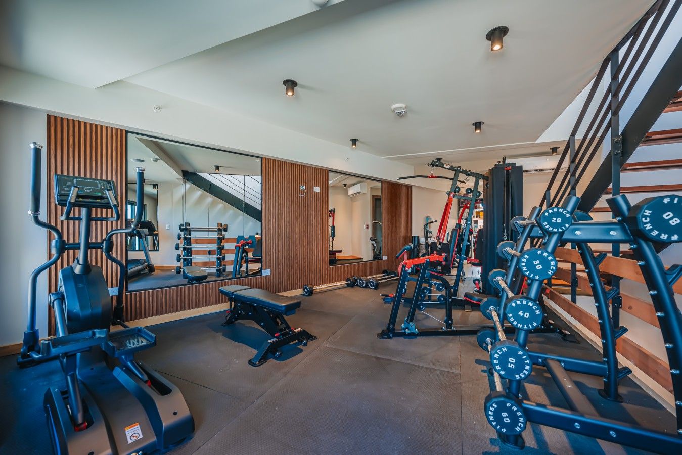 A gym with exercise equipment, a bench, and a mirror.