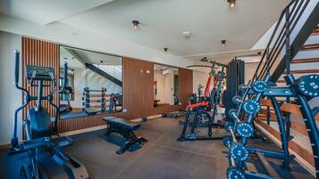 A gym with exercise equipment, a bench, and a mirror.