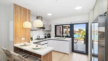 A modern kitchen with a central island, white cabinetry, and a view of an outdoor swimming pool.