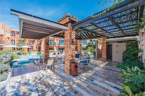 Un espace aménagé au bord de la piscine, avec des sièges extérieurs et un patio couvert.