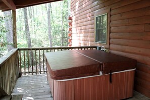 Una vasca idromassaggio su un pontile di legno con vista su una foresta.
