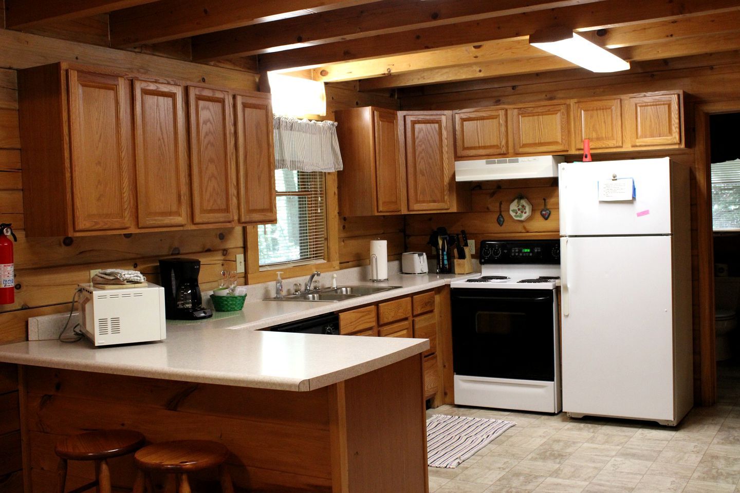 A kitchen with wooden cabinets, a stove, a refrigerator, a microwave, and a coffee maker.