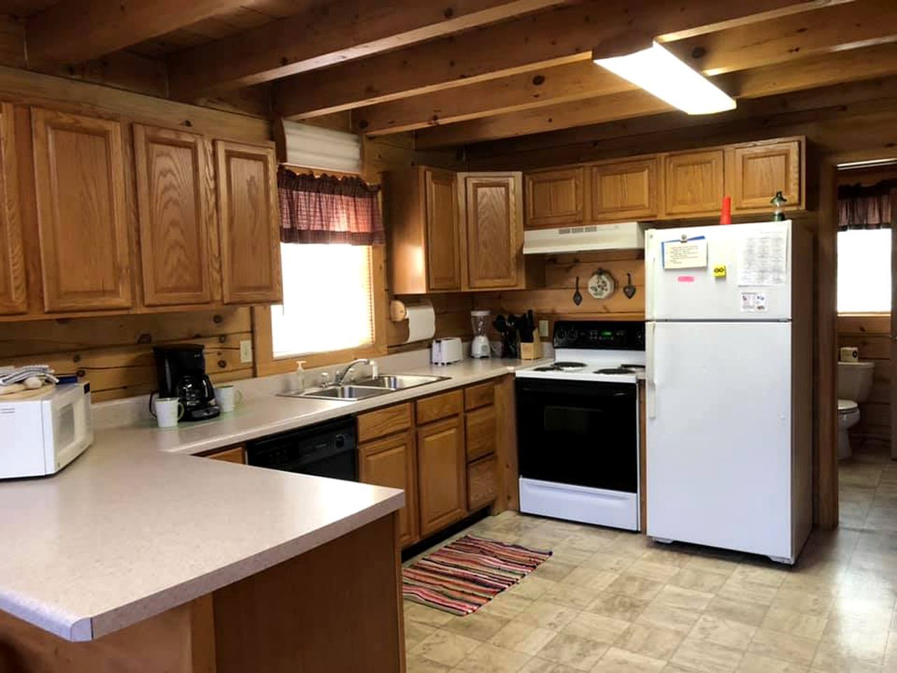 Une cuisine avec des meubles de rangement en bois, un réfrigérateur blanc, une cuisinière et un four à micro-ondes.