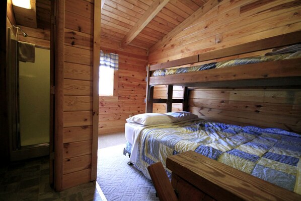Ein Holzhütten-Zimmer mit einem Bett, einer hölzernen Bank und einem kleinen Tisch.