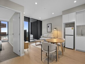 A modern apartment with a dining area, a kitchen, and a balcony with a view. - Skyline 1-bed Apartment Near Melbourne CBD (Melbourne)
