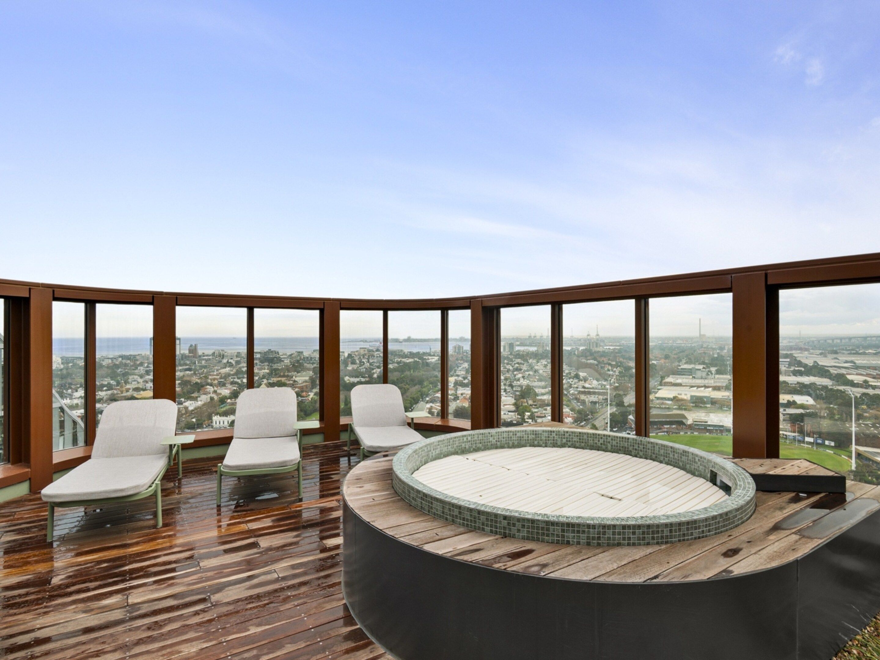 A rooftop terrace with a circular hot tub, lounge chairs, and a panoramic city view.