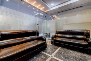 A modern waiting area with leather chairs and a glass partition. - Super Townhouse Lanco Hills Gachibowli (Hyderabad)