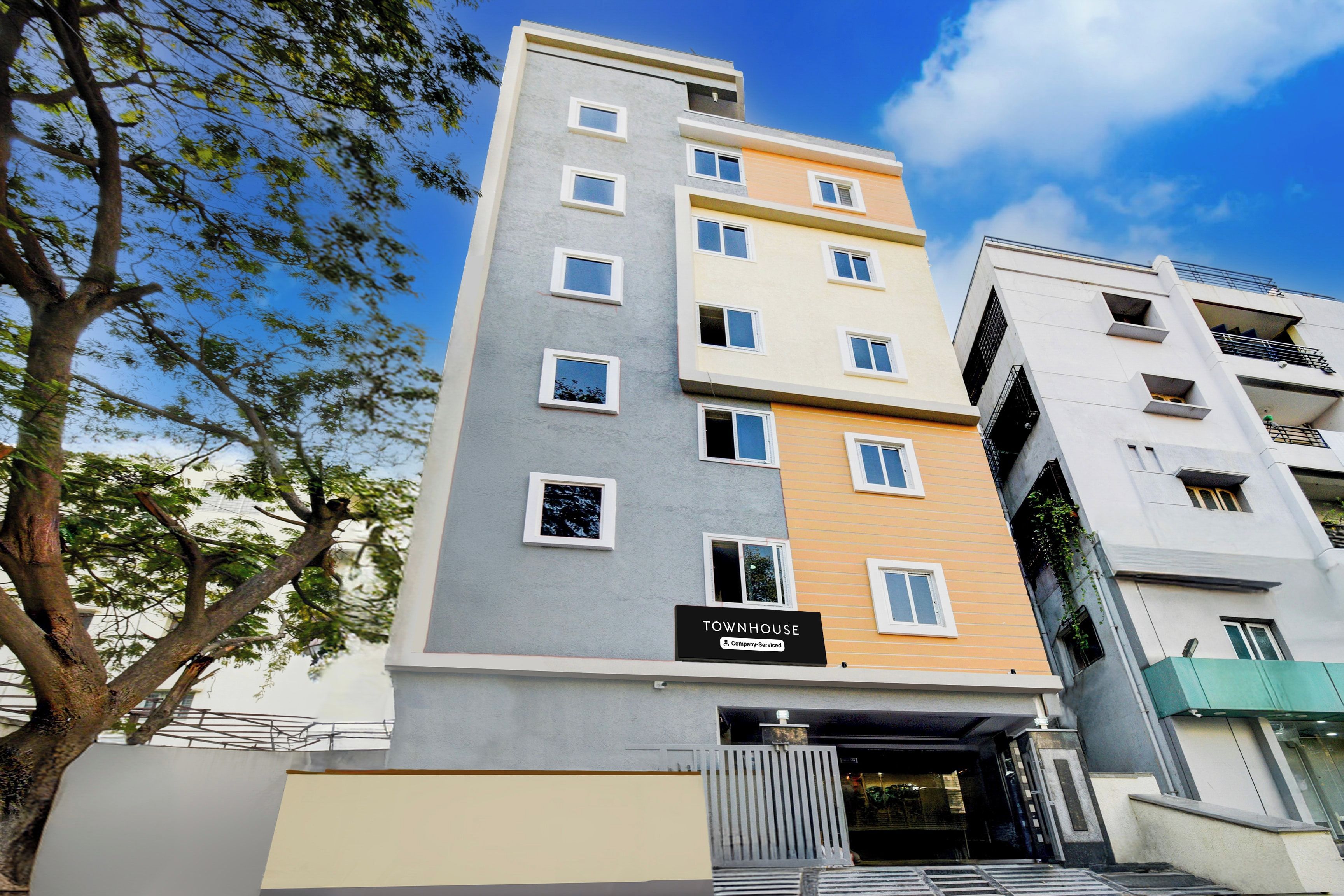 A multi-story residential building with a sign indicating it is a company-serviced townhouse.