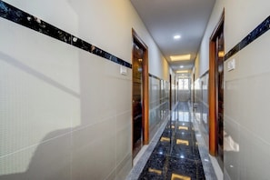 A hotel corridor with a marble floor, glass doors, and a ceiling light. - Super Townhouse Lanco Hills Gachibowli (Hyderabad)