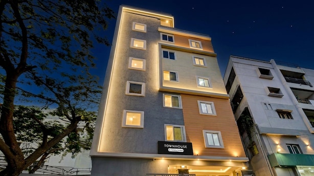 Un hotel de varios pisos con un letrero que dice 'TOWNHOUSE' y una entrada con portones.