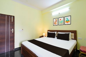 Una habitación de hotel con una cama, una mesita de noche, una lámpara y tres cuadros en la pared.