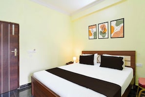 Una habitación de hotel con una cama, una mesita de noche, un teléfono y una lámpara fijada a la pared.
