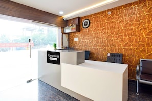 Una mesa de recepción con un cartel que dice 'TOWNHOUSE', un reloj y una cámara de seguridad en la pared.