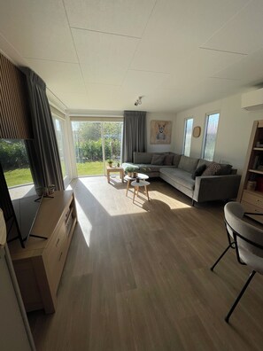 A modern living room with a sofa, a coffee table, and a TV stand. - Chalet Kwispel | Relaxation for you, adventure for your dog (Putten)