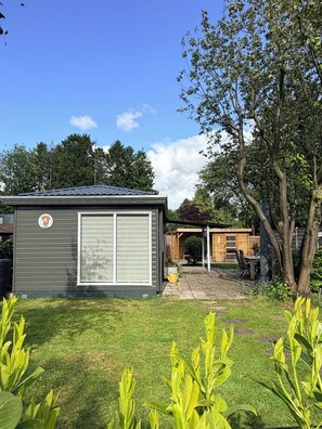 A residential property with a detached garage, a covered patio, and a well-maintained lawn. - Chalet Kwispel | Relaxation for you, adventure for your dog (Putten)